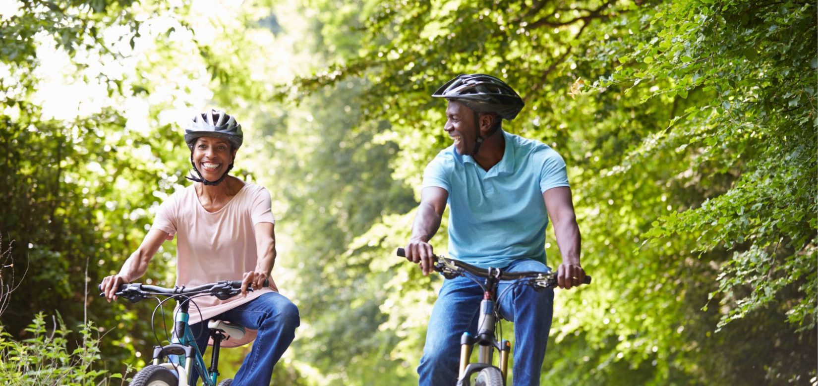 Middle-aged couple smiling while riding bikes on a sunny day