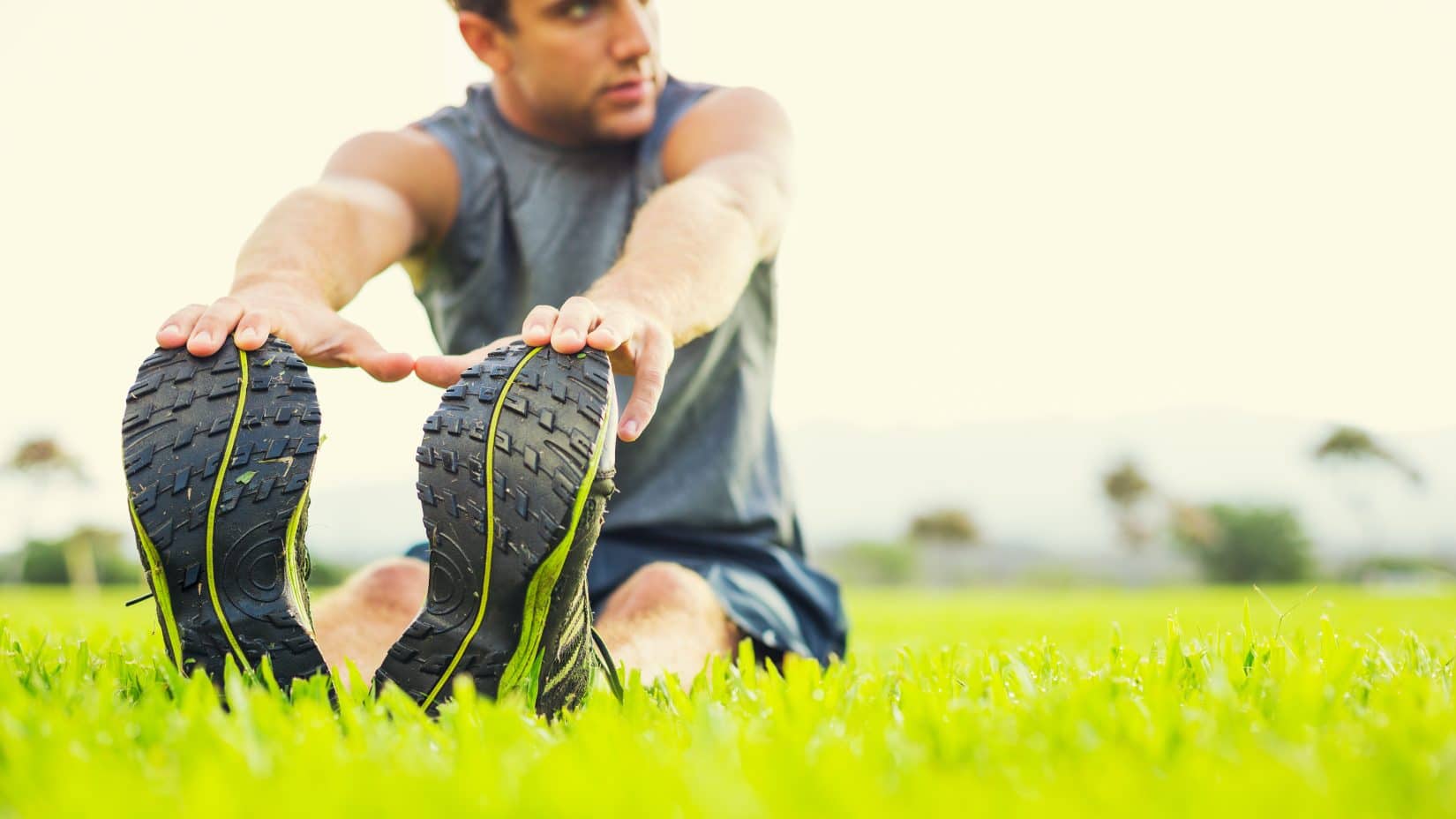 Man in running gear stretching on grass