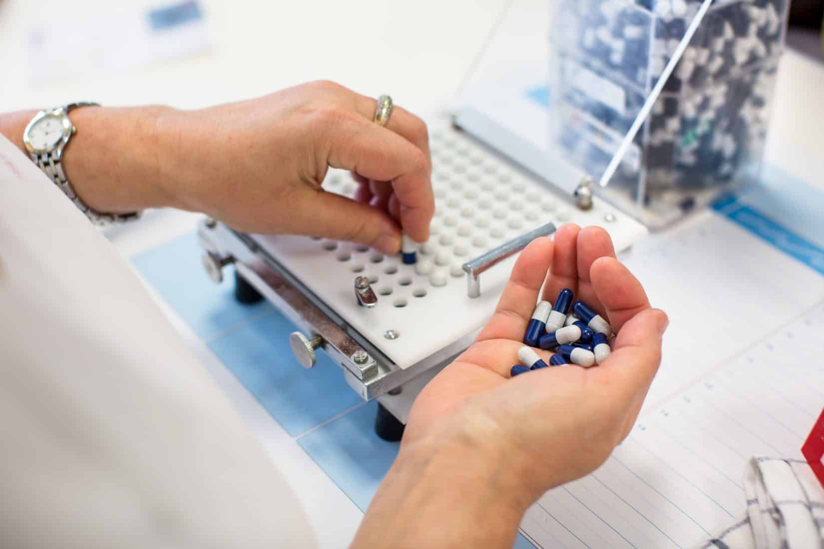 Woman putting pills into a pill counter at a compounding pharmacy